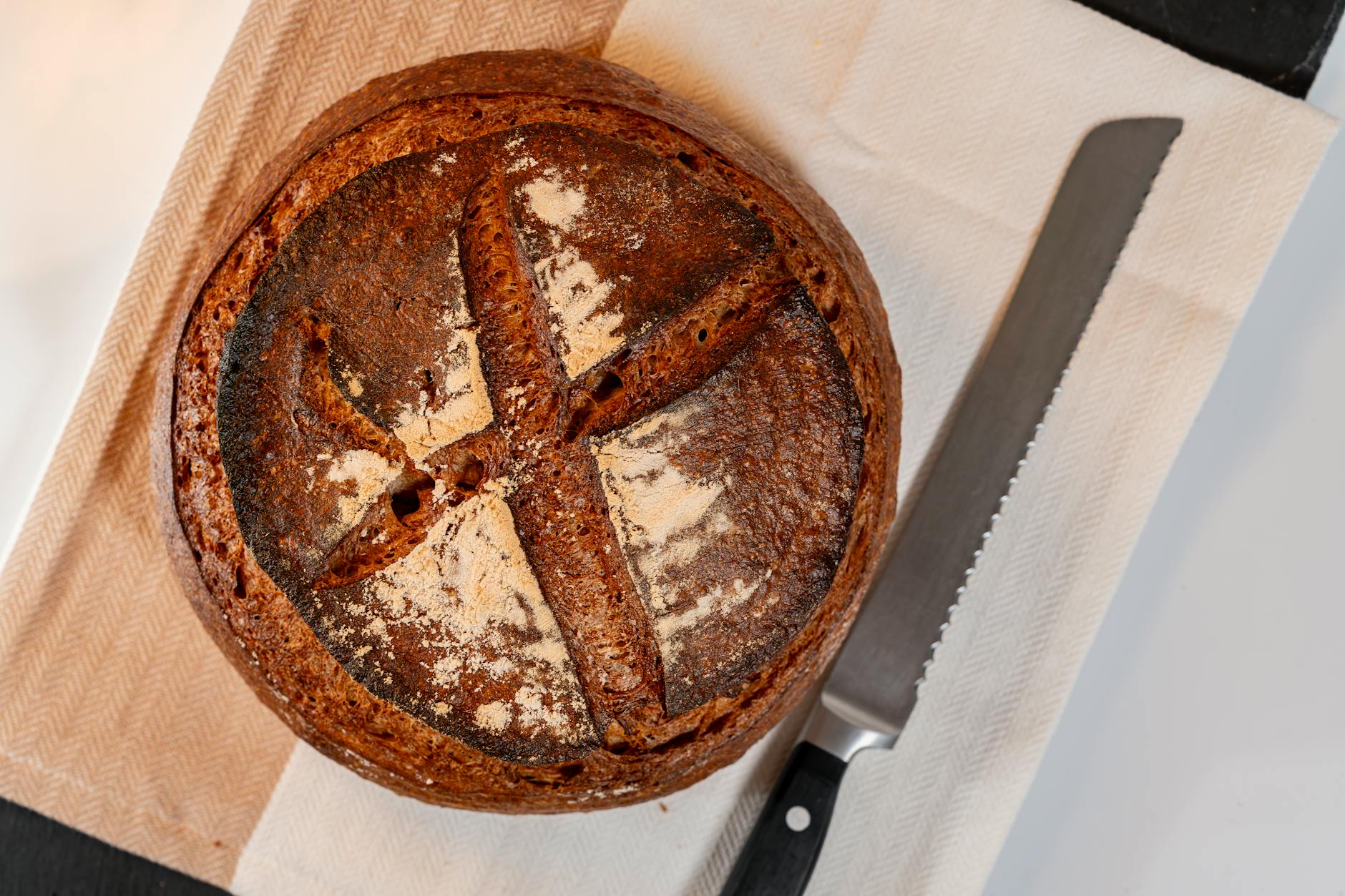Bochenek domowego chleba pszennego na zakwasie na ściereczce z nożem