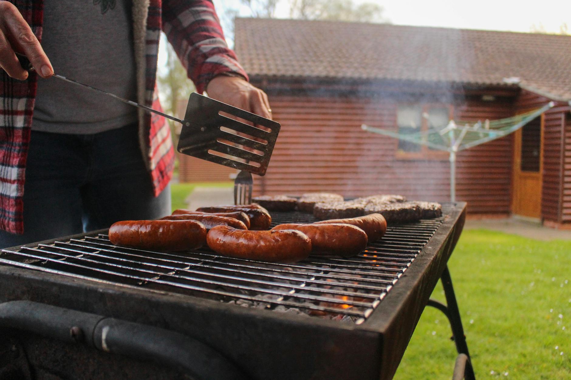Grillowanie kiełbasek i kotletów w ogrodzie przy drewnianym domu